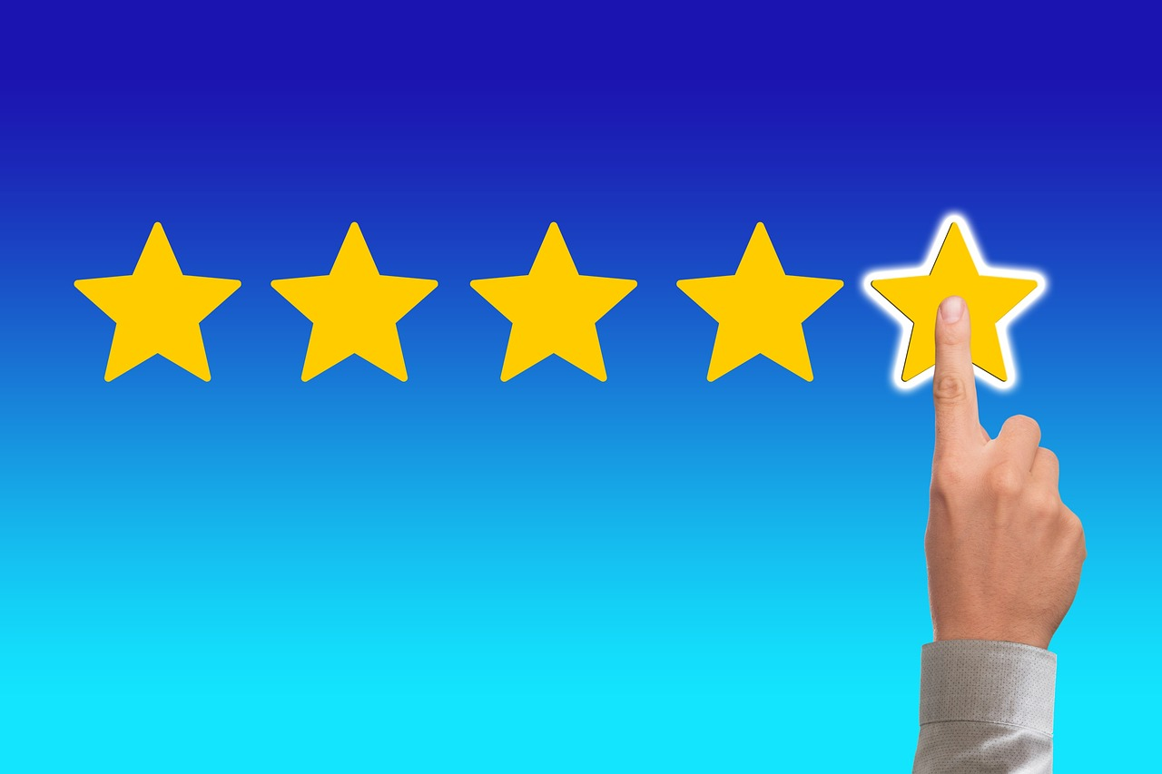 Hand pressing the fifth yellow star to give a perfect five-star rating on a blue background.